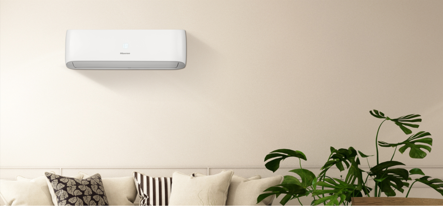 White wall-mounted air conditioner above beige sofa in modern living room, cushions and indoor plants