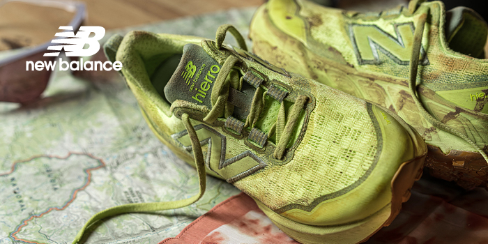 Green New Balance trail running shoes (Hierro) resting on a folded map, lightly muddy and worn