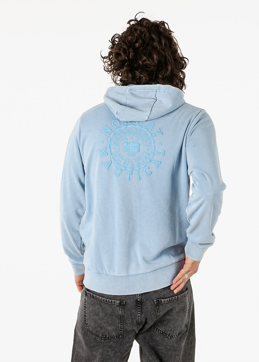Rear view of person wearing light blue hooded sweatshirt with embossed circular "Nautical" logo and faded black jeans