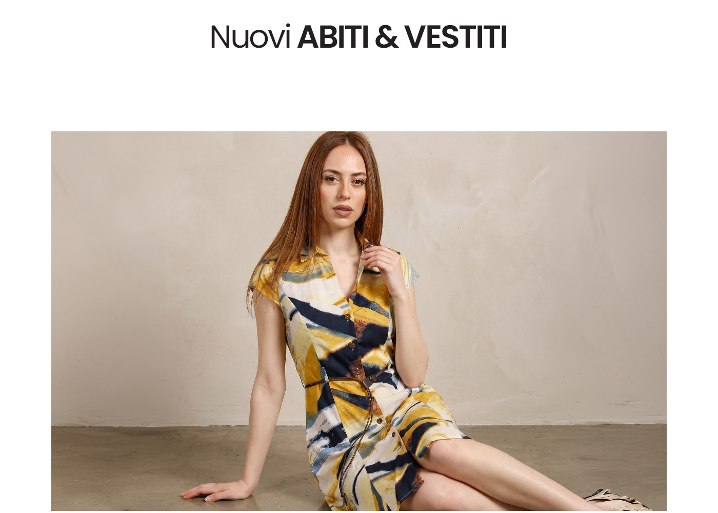Model seated on studio floor wearing yellow and navy abstract-print summer dress, short sleeves, knee length