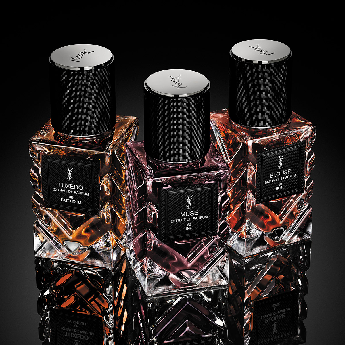 Tre flaconi di YSL Extrait de Parfum su una superficie nera riflettente.
