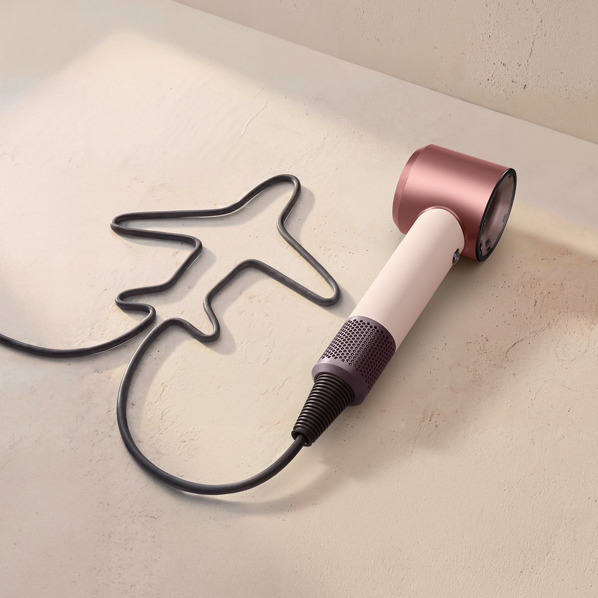 Dyson Supersonic Travel hair dryer with the cable shaped to resemble an aeroplane.