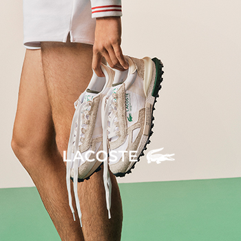 Person holding white and beige Lacoste sneakers with green crocodile logo and textured black sole against pale green and cream background