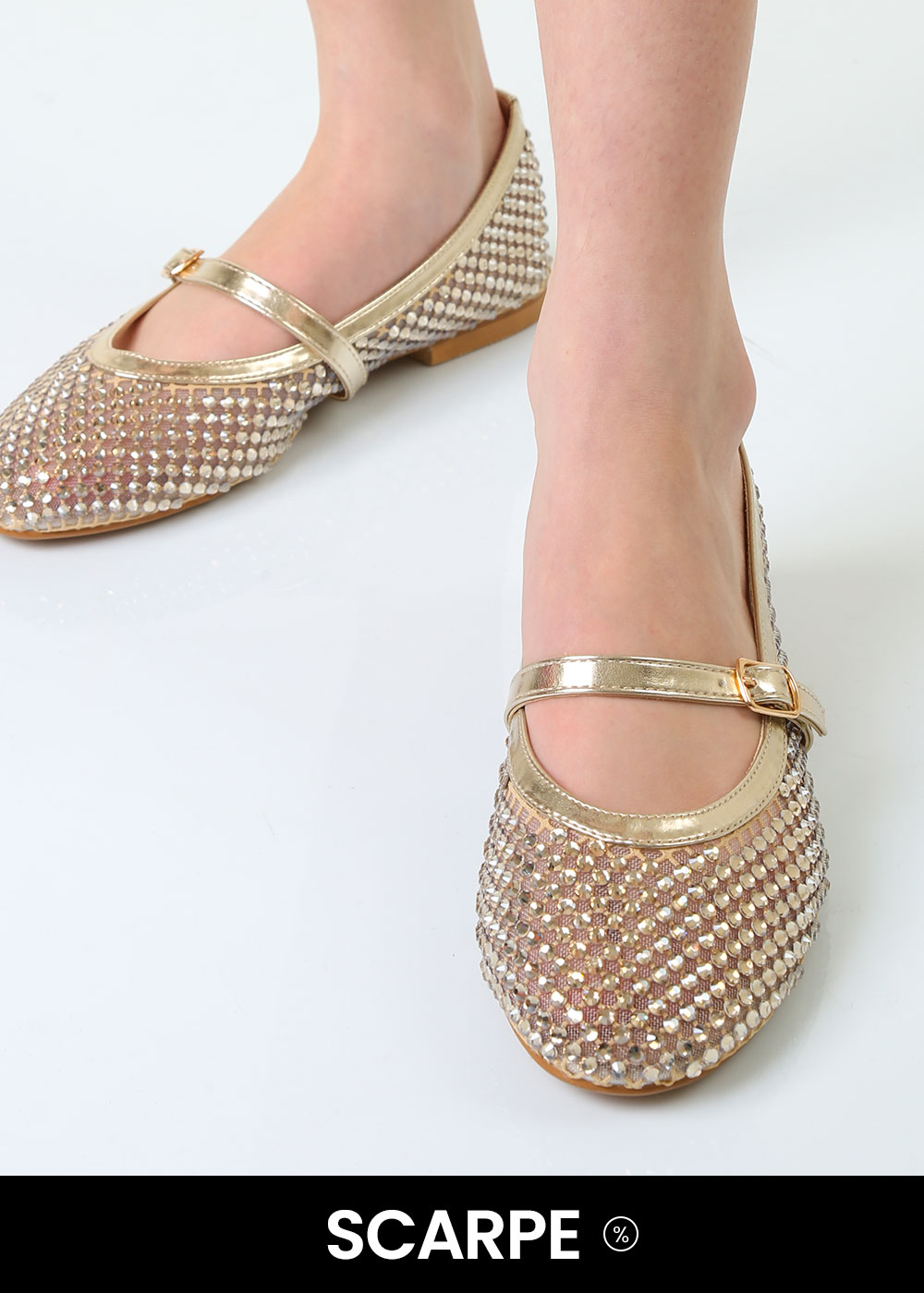 Close-up of gold glitter Mary Jane ballet flats with buckle strap and rhinestone embellishments worn on feet against a white background