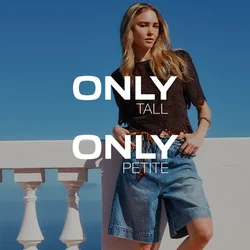 Giovane donna con lunghi capelli biondi che indossa un top nero, pantaloncini di jeans e sandali, si appoggia a una balaustra bianca sotto un cielo azzurro limpido.