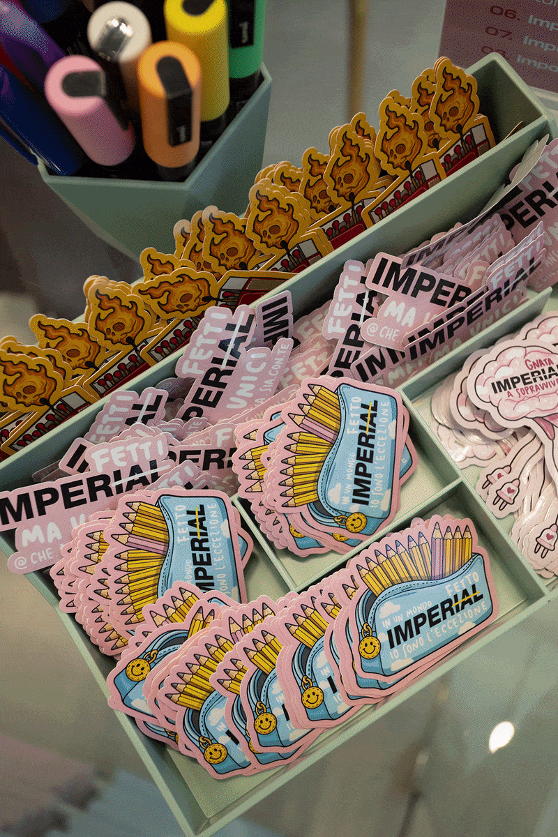 Boutique launch event with models and shoppers amid pastel 'Imperial' product boxes and large pink floral displays inside a department store