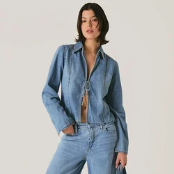 Outfit in denim composto da un giubbotto cropped azzurro con chiusura a bottoni e jeans a gamba larga a vita alta. Abbinato a una borsa blu coordinata.