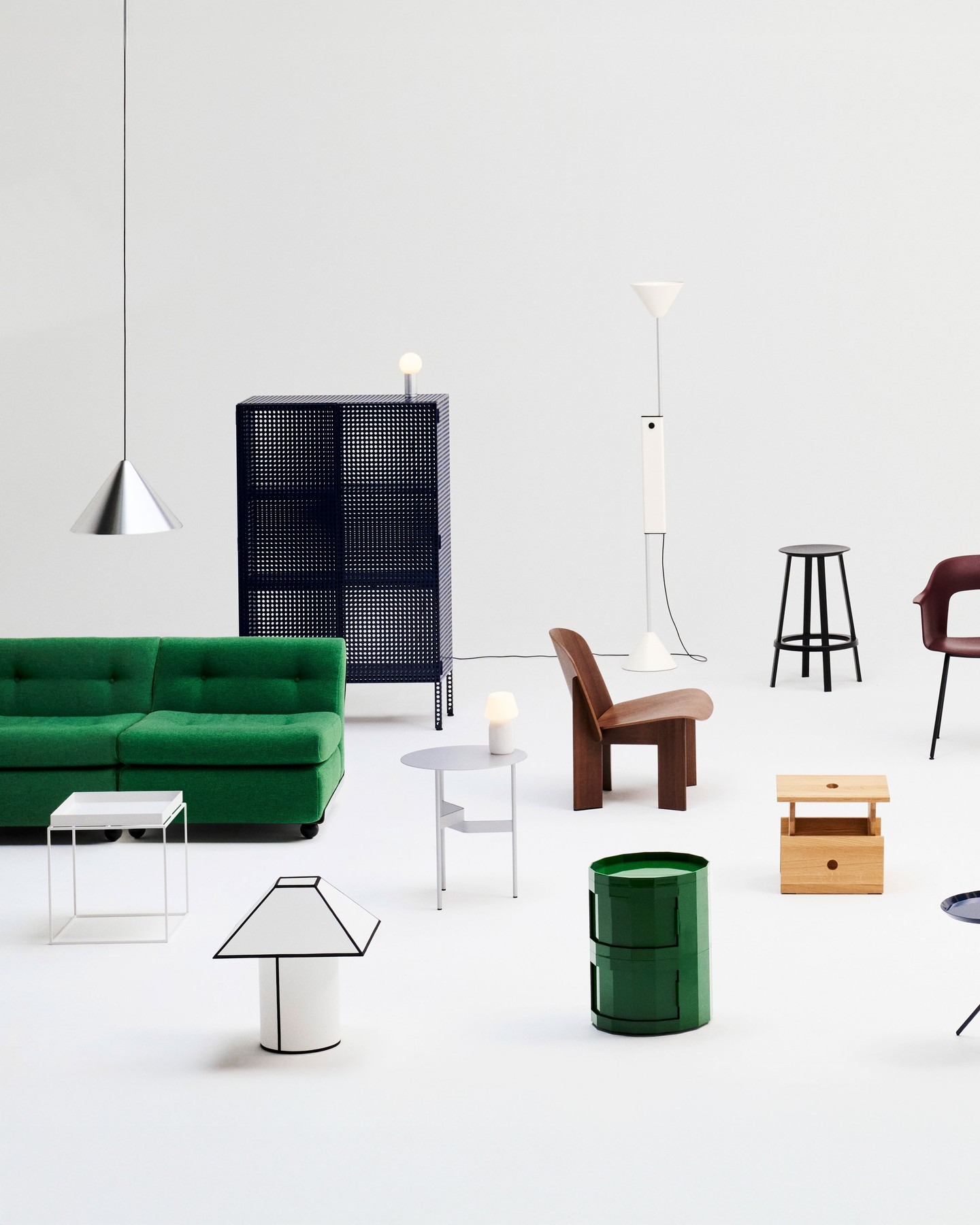Minimalist showroom of modern furniture on white background: green sofa, designer chairs, lamps, side tables and stools