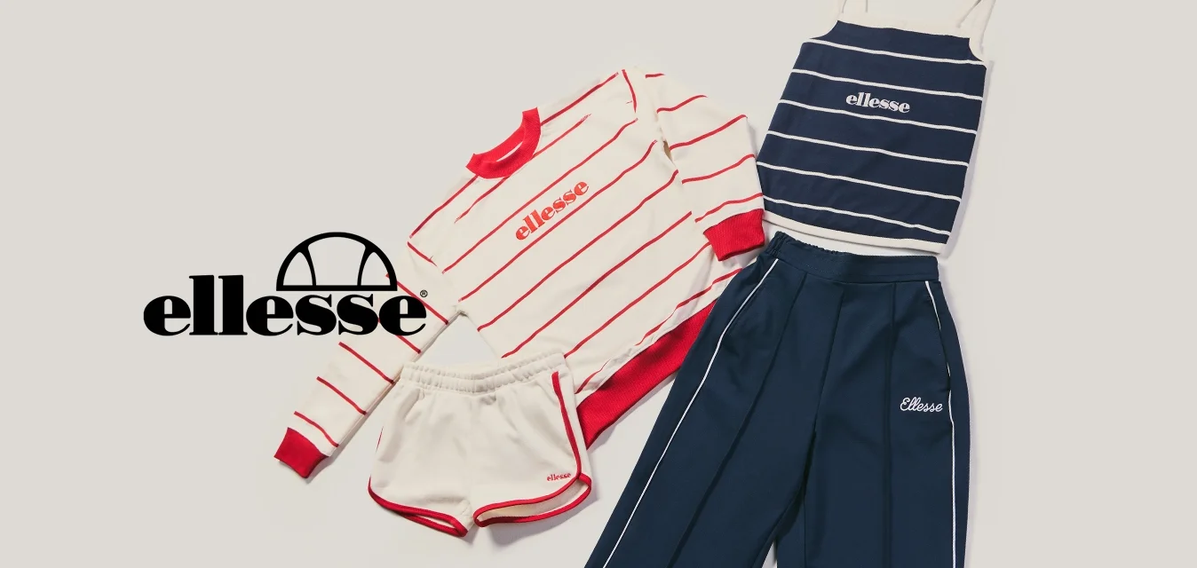 Completo sportivo casual con felpa a righe rosse, pantaloncini bianchi, canotta a righe blu navy e pantaloni della tuta blu navy disposti su uno sfondo chiaro.