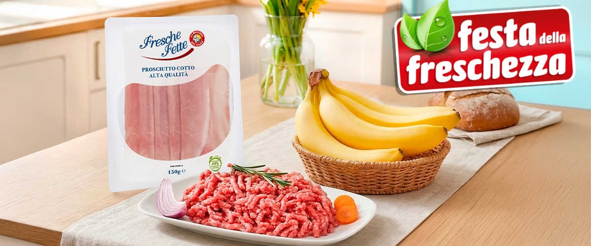Kitchen counter with packaged sliced ham, raw minced beef on a plate, basket of bananas and bread with freshness promo