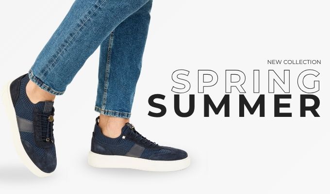 Feet wearing rolled blue jeans and navy blue casual sneakers on white background with “Spring Summer” new collection text