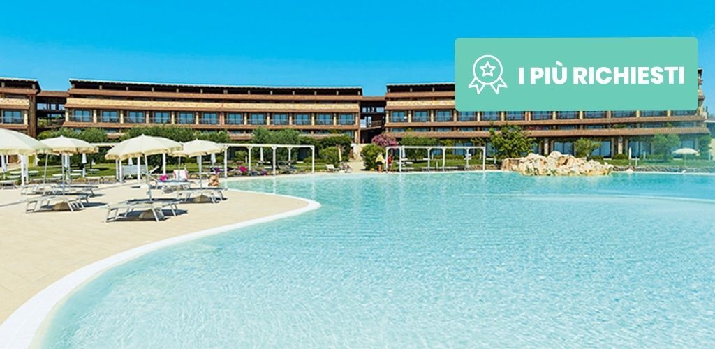 Resort's large turquoise swimming pool with sunbeds and parasols on the deck, modern hotel building and clear blue sky