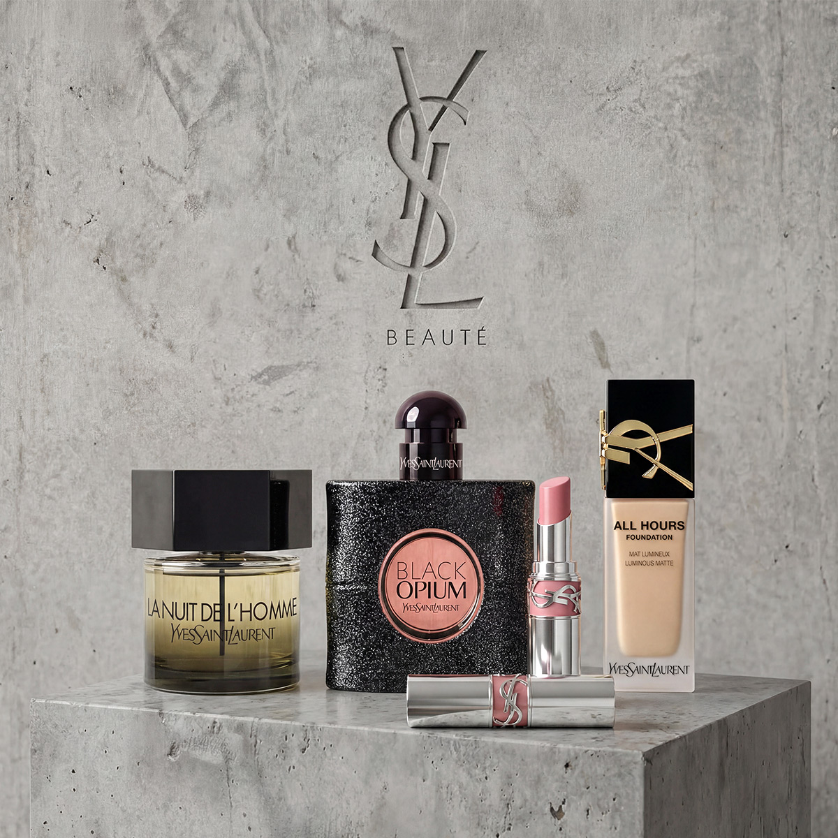 Une collection de parfums, rouge &agrave; l&egrave;vres et fond de teint YSL pr&eacute;sent&eacute;s sur un pi&eacute;destal en pierre grise.
