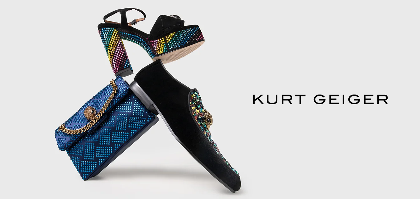 Scarpe nere con tacco alto, dotate di un cinturino a motivo multicolore e dettagli gioiello, abbinate a una borsa blu in tessuto con manico a catena.