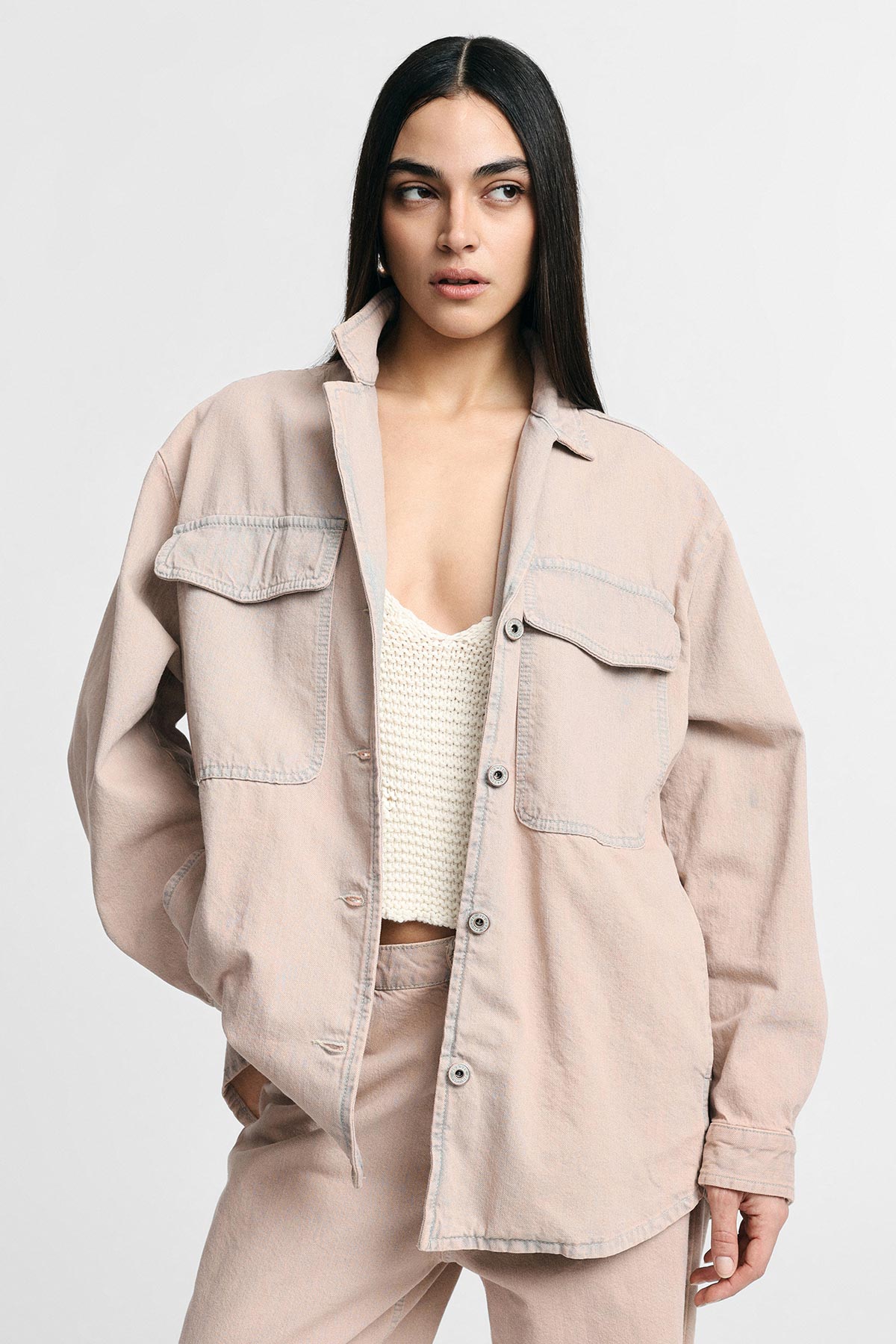 Woman modelling oversized pale pink denim shacket and matching trousers over a cream knitted crop top against a neutral background