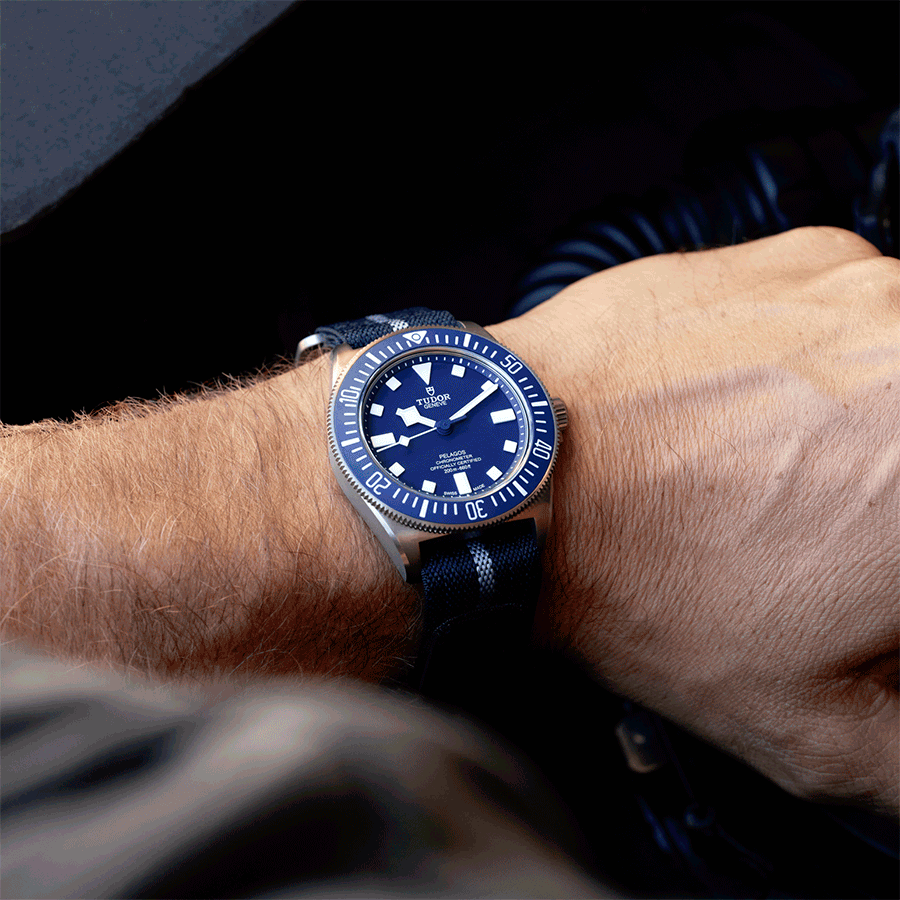 Blue diver watch with striped nylon strap shown on wrist and flatlay; waterproof scuba watch worn by diver at sea