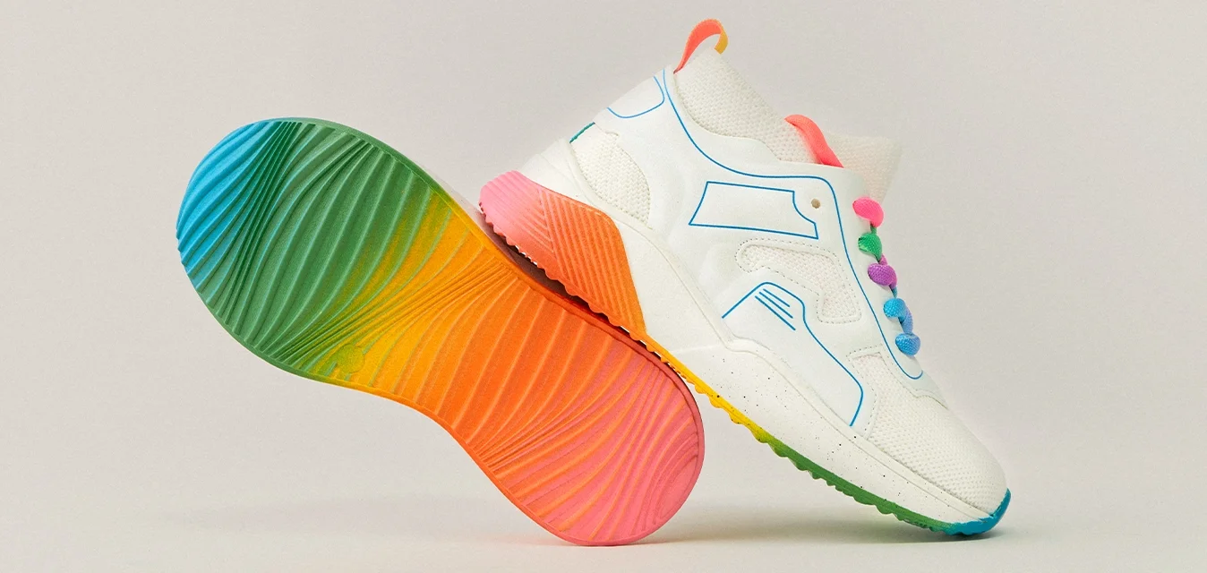 Sneaker bianco con accenti blu, caratterizzato da una suola arcobaleno testurizzata con sezioni a gradiente di rosa, arancione, verde e blu.