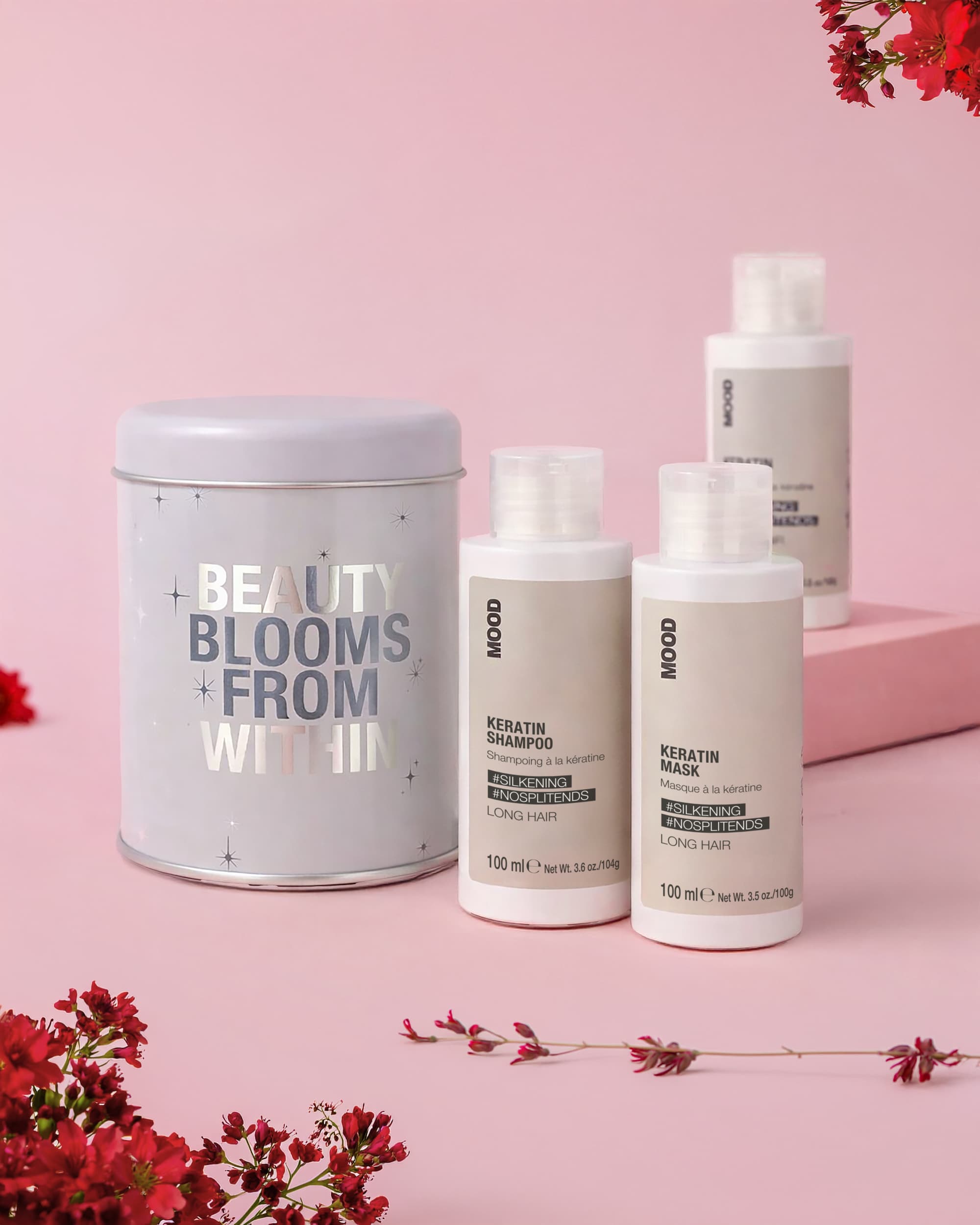 Cofanetto di latta grigio con scritte argento, shampoo e conditioner e mask packaging grigio formato travel size, fiori di campo rossi, sfondo rosa