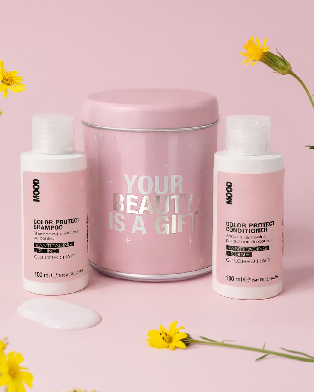 Cofanetto di latta rosa con scritte argento, due shampoo e conditioner packaging rosa formato travel size, goccia di shampoo, fiori di campo gialli, sfondo rosa