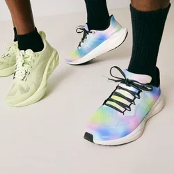 Due persone che indossano calze nere e scarpe da ginnastica colorate, in piedi su un pavimento chiaro contro uno sfondo uniforme.