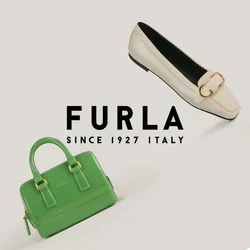 Piccola borsa in pelle verde accanto a un mocassino color crema con fibbia dorata su uno sfondo bianco neutro.