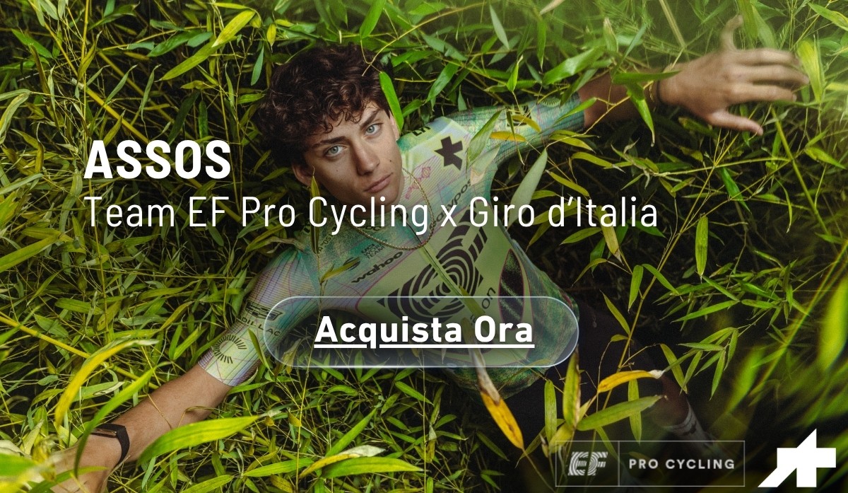 Young cyclist in colourful ASSOS racing kit lying in tall grass, promotional banner for Team EF Pro Cycling x Giro d'Italia with “Acquista Ora” button