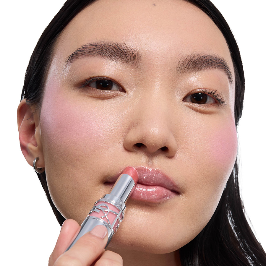 Una modella applica un rossetto rosa YSL sulle labbra.