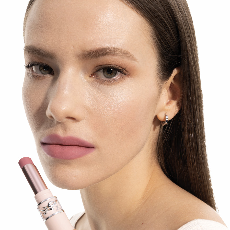 Una modella posa con un rossetto rosa YSL.