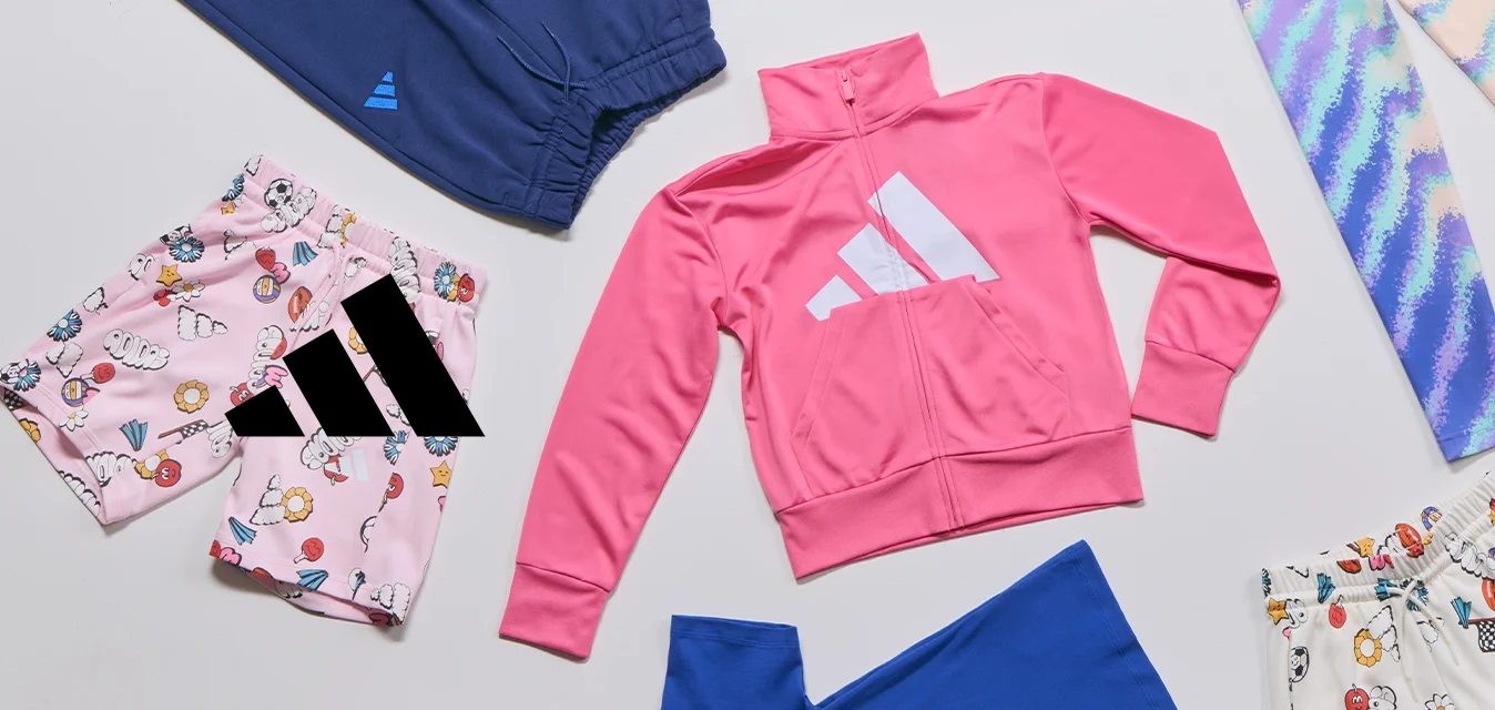Variati articoli di abbigliamento per bambini, tra cui una giacca rosa con zip, pantaloni corti con fantasia e leggings multicolori, disposti su una superficie bianca.