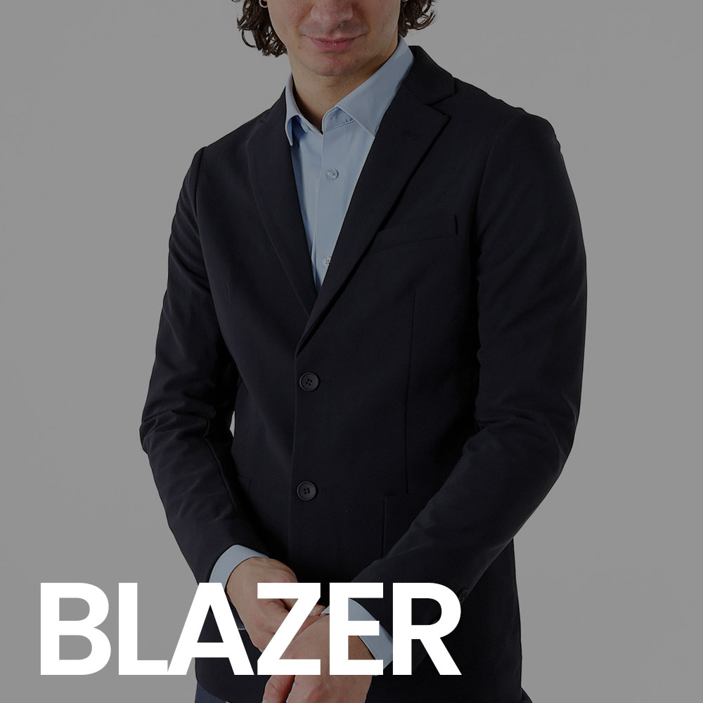 Male model wearing a navy blazer over a light blue shirt, buttoned and hands clasped, product studio shot