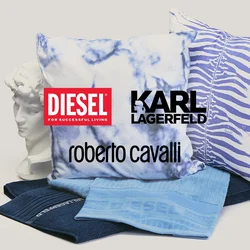 Due cuscini decorativi con motivi blu, due tessuti blu piegati e un busto bianco in stile classico su sfondo neutro.