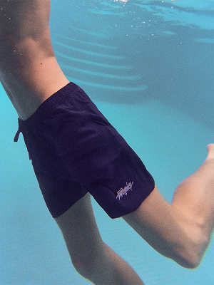 Modello con pantaloncini da bagno blu navy sott’acqua.