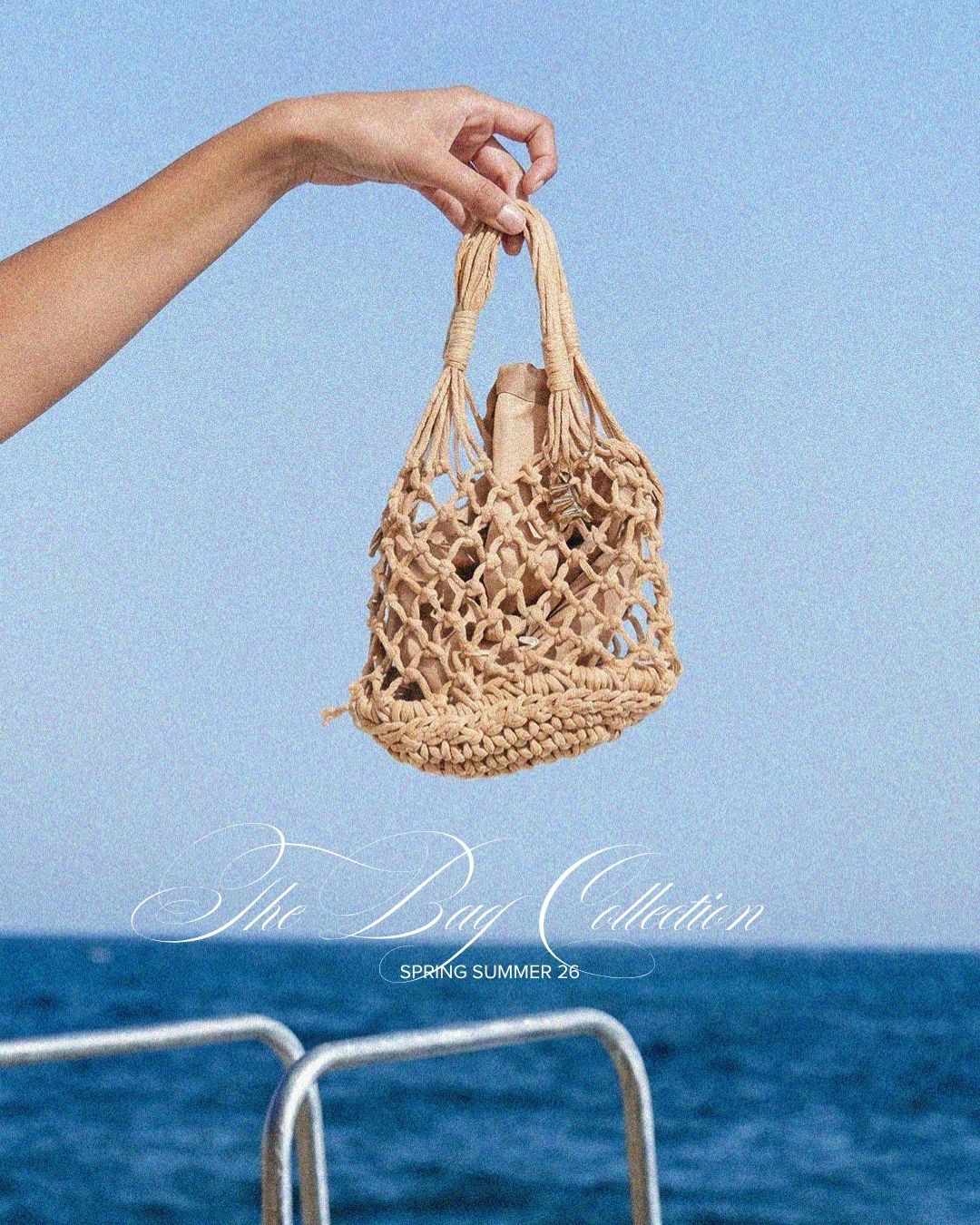 Hand holding a woven macramé beach bag against blue sky and sea, summer accessory for casual seaside outfits