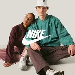Due giovani adulti seduti sul pavimento, uno appoggia la testa sulla spalla dell'altro, entrambi indossano abbigliamento sportivo casual e sneakers.