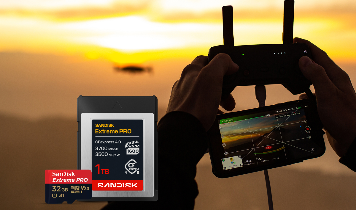 Una scheda SanDisk Extreme PRO CFexpress e una scheda microSD SanDisk Extreme PRO visualizzate accanto a una persona con in mano il telecomando di un drone e uno smartphone che mostra filmati con un drone sullo sfondo del tramonto.