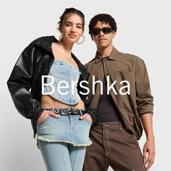 Due persone stanno fianco a fianco. Uno indossa una giacca di pelle nera e un top in denim corta con jeans a vita alta. L'altro indossa una camicia marrone e pantaloni.