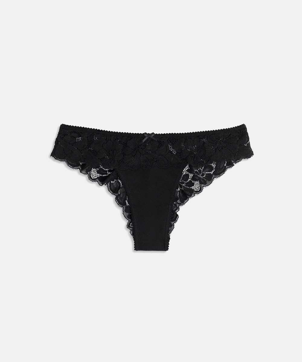 Black lace women's thong with scalloped edges and small bow, flat lay on white background