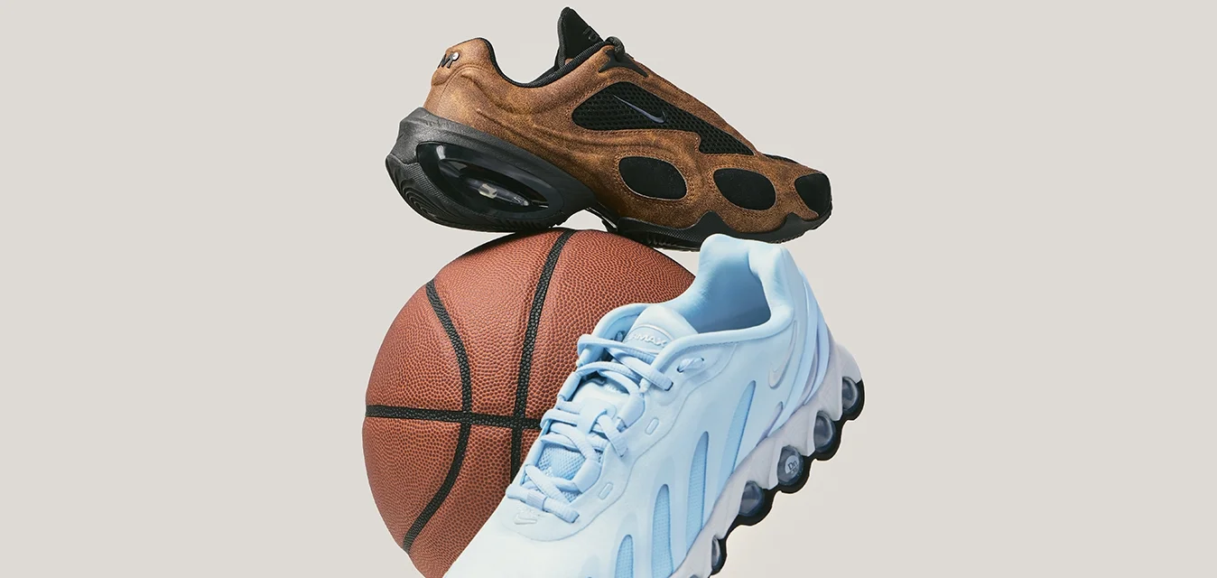 Scarpe da ginnastica marroni e azzurro chiaro appoggiate su un pallone da basket su uno sfondo grigio chiaro uniforme.