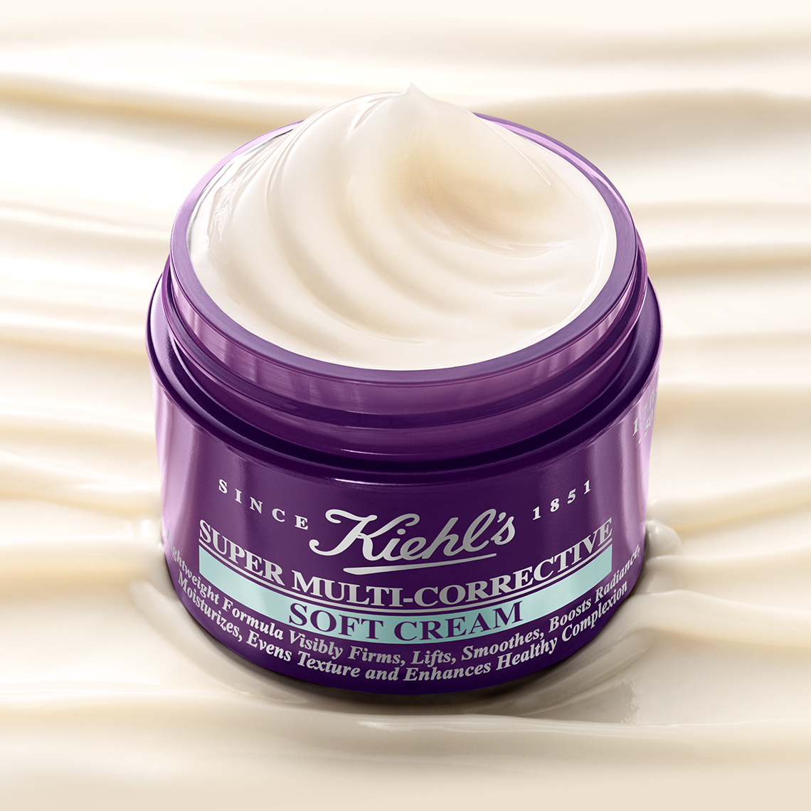 Vasetto viola aperto di Kiehl's Super Multi-Corrective Soft Cream, immerso in una texture di crema soffice. 