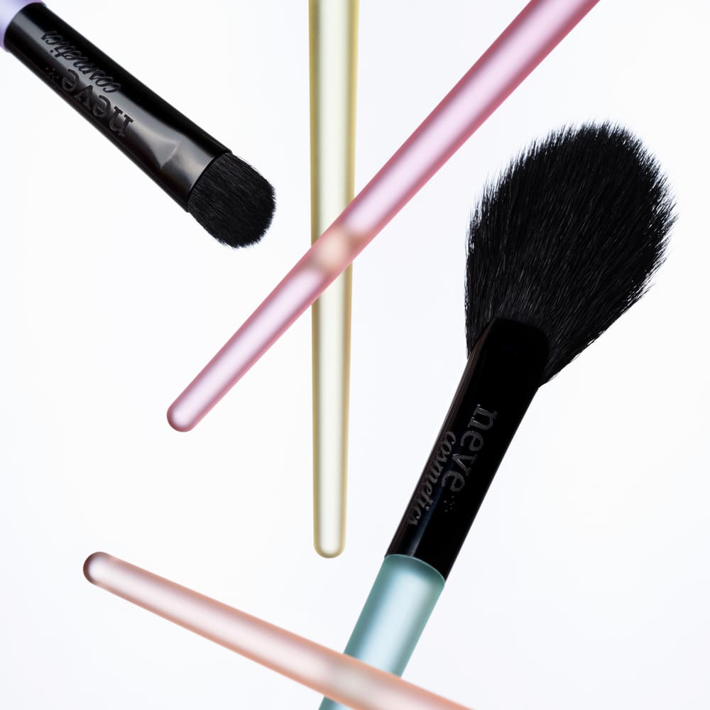 Set of five make-up brushes with black bristles and colourful pastel handles floating on a white background, cosmetic brush kit