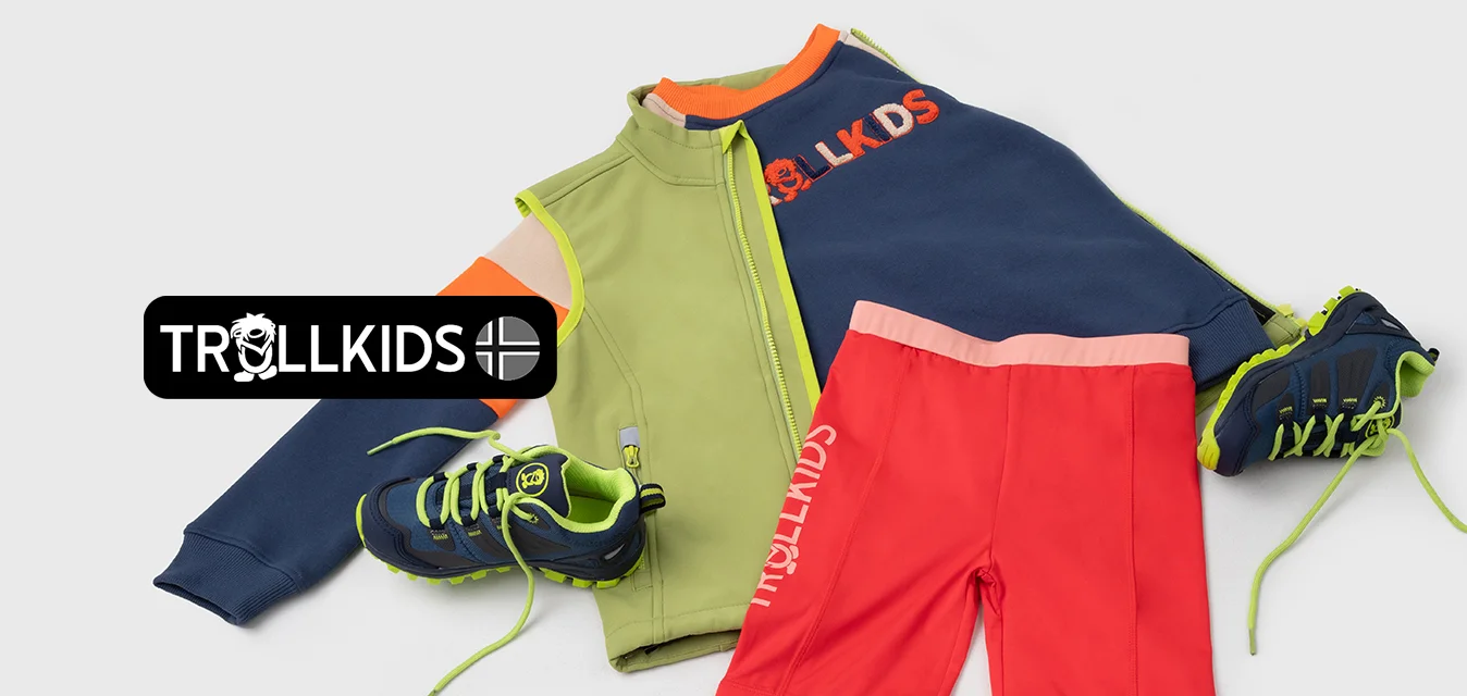 L'outfit sportivo colorato include una giacca verde e blu navy, pantaloni corti rossi e scarpe nere con lacci verde neon, caratterizzato da texture e design vari.