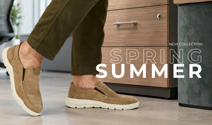 Tan suede slip-on casual shoes worn with olive pants on an office floor, modern spring–summer collection