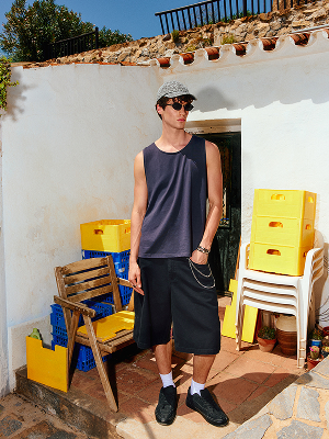 Modello con canotta, shorts lunghi e cappellino.