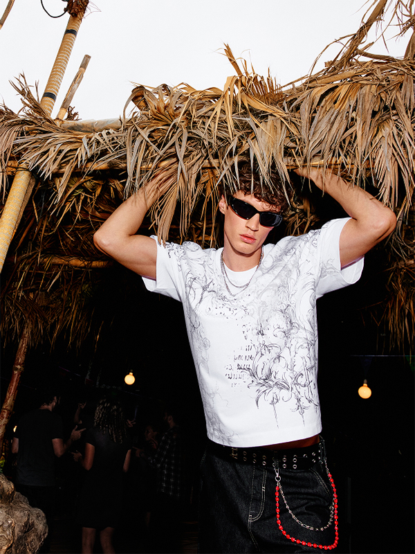 Modello con T-shirt bianca stampata e shorts lunghi neri.