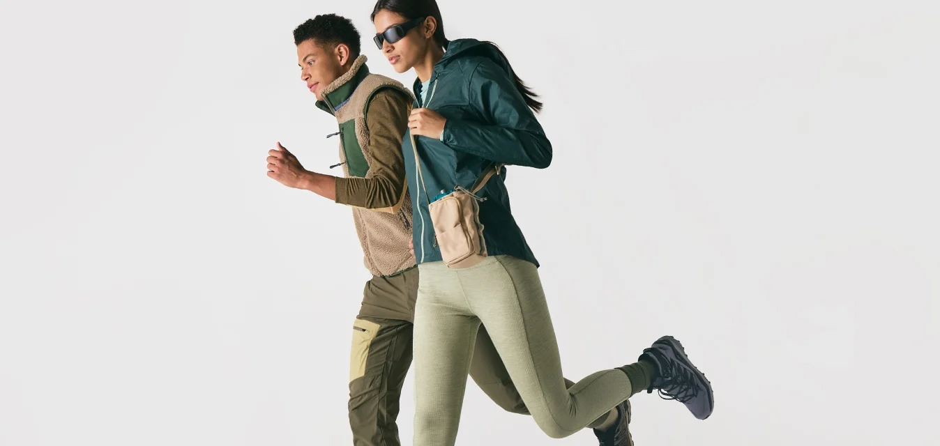 Due persone vestite con abbigliamento sportivo e scarpe da ginnastica, che corrono affiancate su uno sfondo bianco.