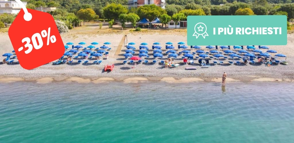 Aerial view of pebble beach with rows of blue umbrellas and sunbeds, turquoise sea; red -30% sale tag and 'I PIÙ RICHIESTI' badge