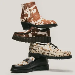 Pila di quattro scarpe con vari motivi, tra cui stampa marrone e bianca di mucca, stampa leopardata e marrone scuro uniforme, su uno sfondo chiaro.