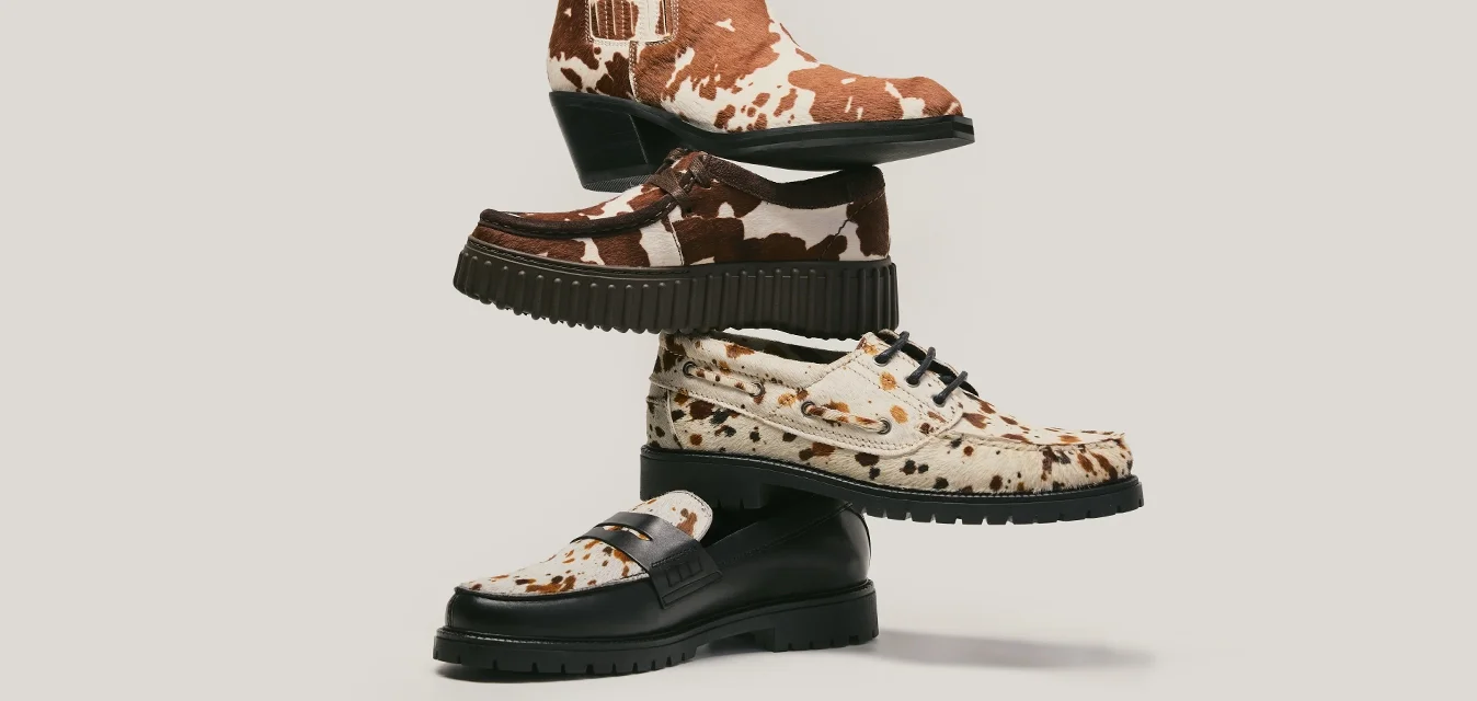 Pila di quattro scarpe con vari motivi, tra cui stampa marrone e bianca di mucca, stampa leopardata e marrone scuro uniforme, su uno sfondo chiaro.