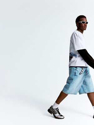 Modello con T-shirt bianca e shorts lunghi in denim.