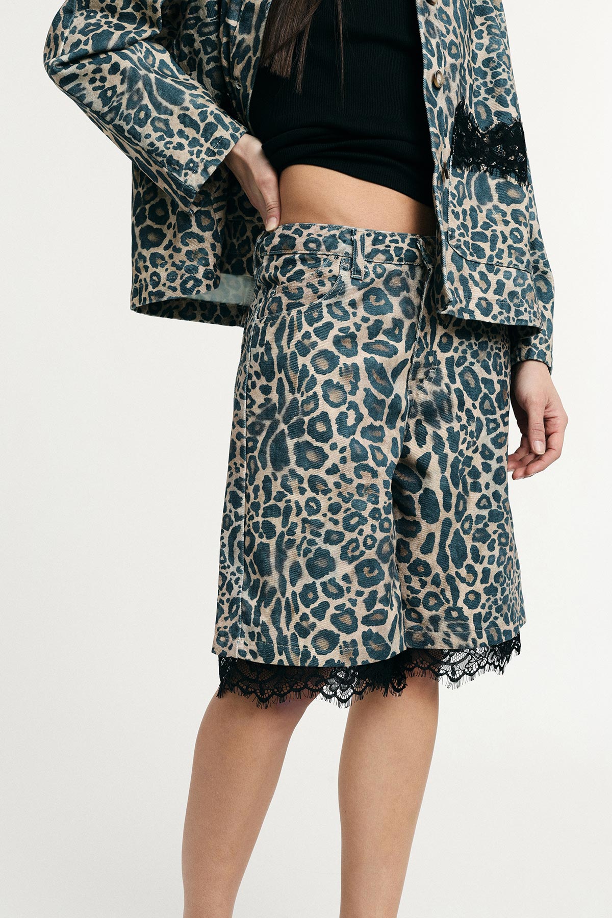 Cropped view of model wearing leopard-print jacket and matching knee-length shorts with black lace trim and black top